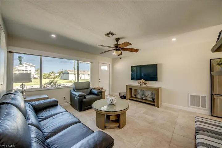 Living room featuring a ceiling fan, light tile patterned floors, recessed lighting, and a textured ceiling