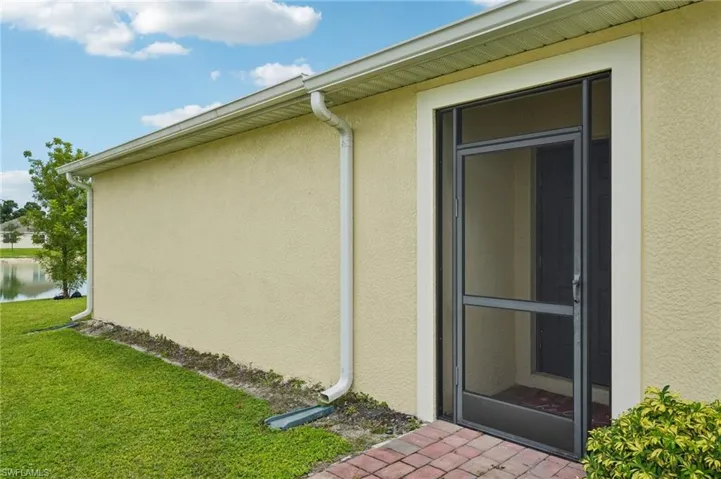 View of home's exterior with stucco siding, a yard, and a water view