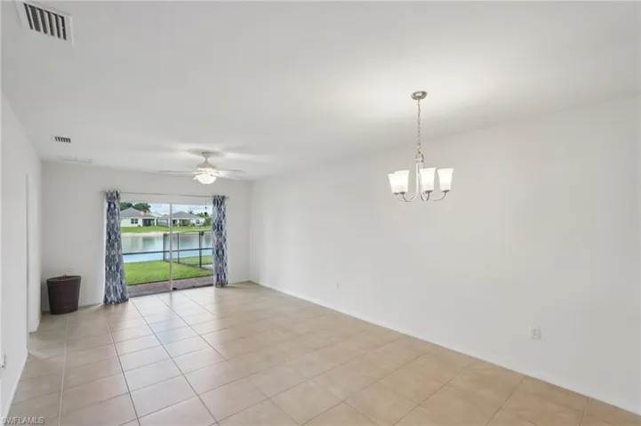 Spare room featuring a water view, light tile patterned flooring, ceiling fan, and a chandelier