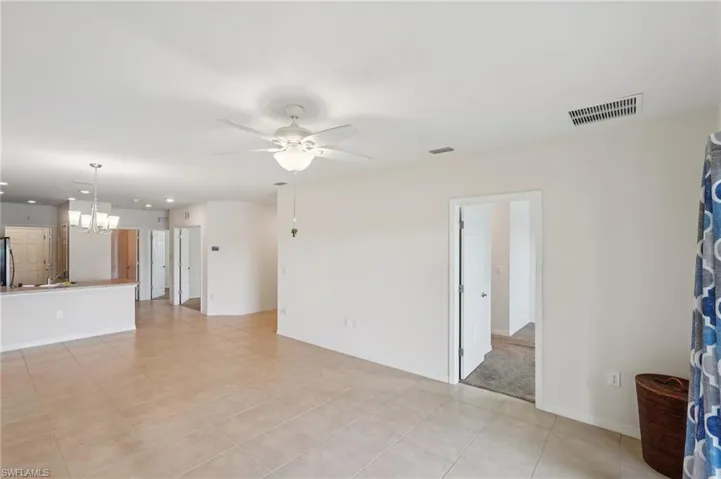 Unfurnished living room featuring a chandelier, a ceiling fan, and light tile patterned floors
