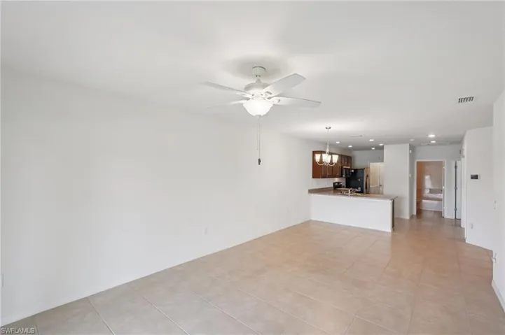Unfurnished living room with a chandelier, light tile patterned floors, recessed lighting, and a ceiling fan