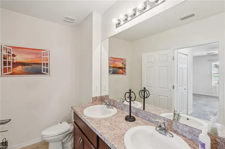 Bathroom with double vanity and baseboards
