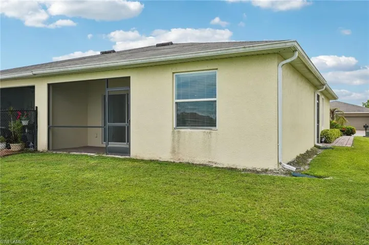 Rear view of house with a yard, stucco siding, and a sunroom