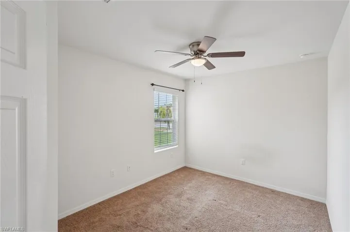 Carpeted spare room with baseboards and ceiling fan
