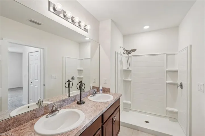 Full bathroom with double vanity, a shower stall, a closet, and light tile patterned floors