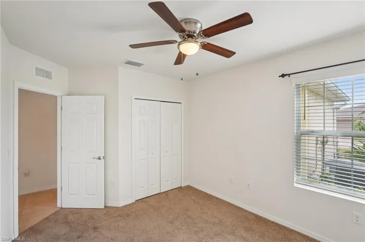 Unfurnished bedroom featuring light carpet, a ceiling fan, and a closet
