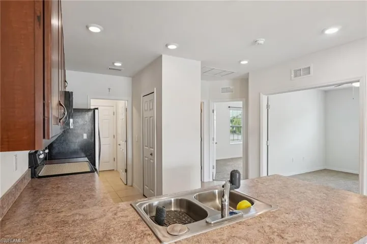 Kitchen featuring recessed lighting, range, light countertops, light tile patterned floors, and light carpet