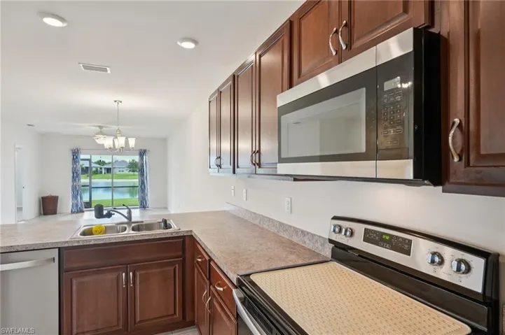 Kitchen featuring stainless steel appliances, light countertops, pendant lighting, a chandelier, and recessed lighting