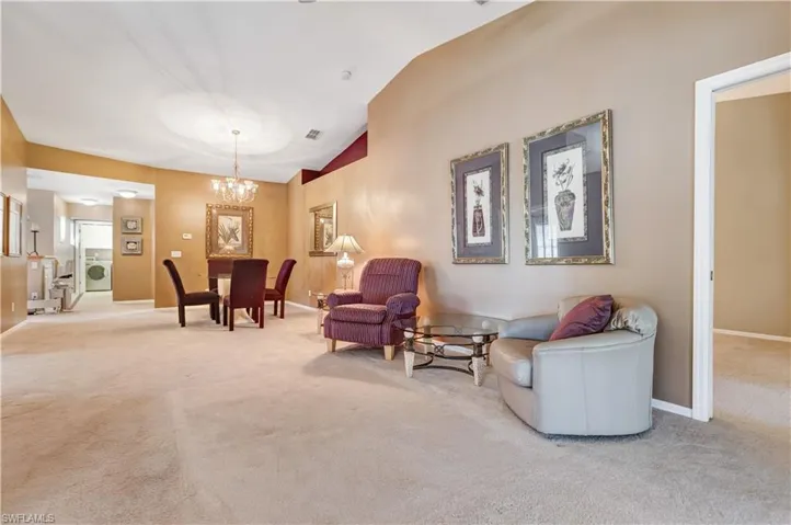 Living area featuring carpet flooring, lofted ceiling, a chandelier, and washer / dryer