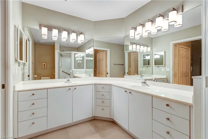 Bathroom featuring double vanity, a shower stall, light tile patterned floors, and a closet