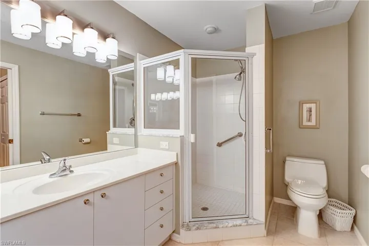 Bathroom with a shower stall, light tile patterned floors, and vanity