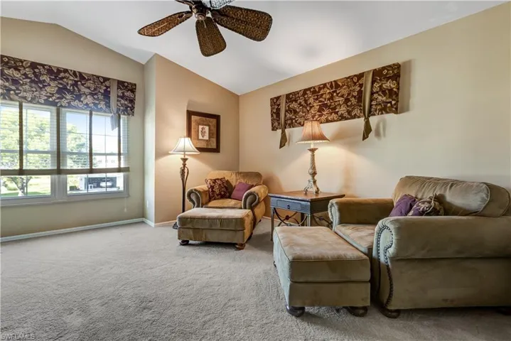 Sitting room featuring lofted ceiling, carpet, and a ceiling fan