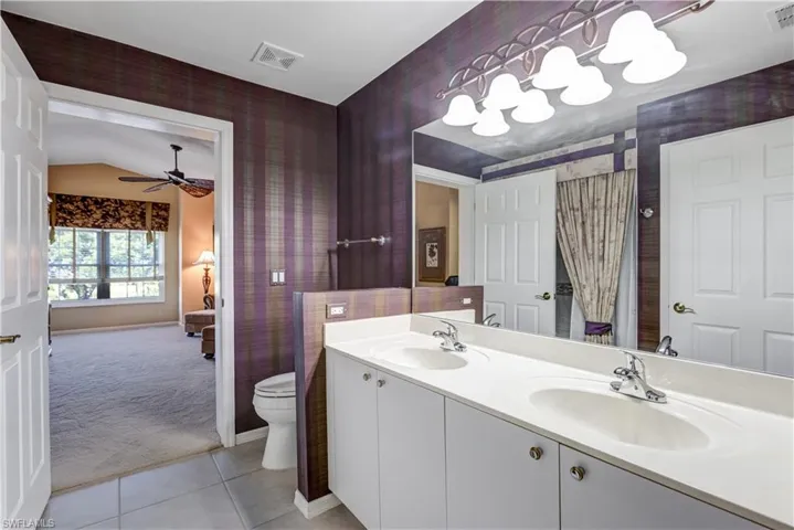 Full bathroom featuring light colored carpet, double vanity, light tile patterned floors, wallpapered walls, and a ceiling fan