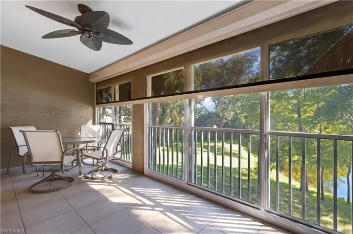 Sunroom / solarium featuring tile patterned floors and view of wooded area
