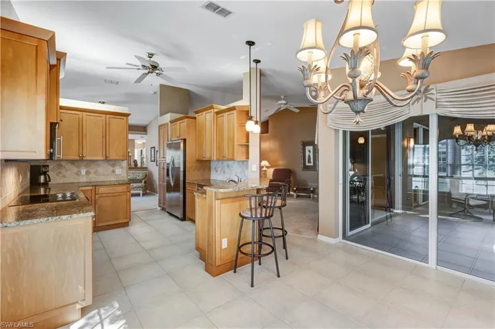 Kitchen featuring a breakfast bar area, a ceiling fan, hanging light fixtures, a peninsula, and a chandelier