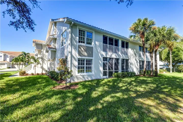 Rear view of property featuring stucco siding, a lawn, and a tile roof