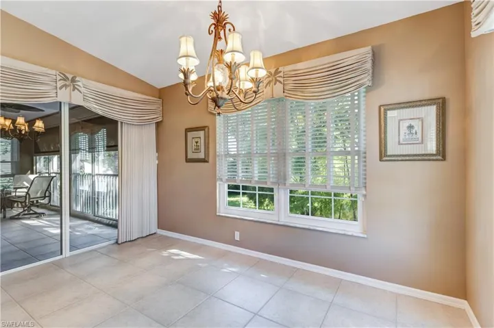 Unfurnished dining area featuring a chandelier, tile patterned floors, and lofted ceiling