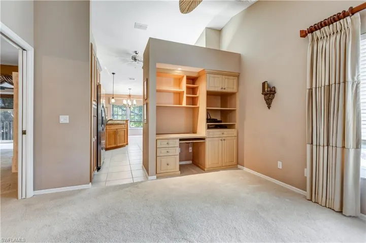 Unfurnished office featuring light carpet, ceiling fan, a chandelier, light tile patterned floors, and built in desk
