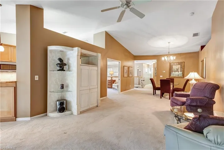 Living room featuring a ceiling fan, light carpet, a chandelier, and high vaulted ceiling