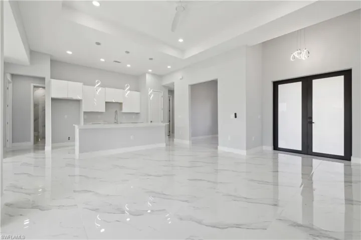 Unfurnished living room featuring a chandelier, french doors, a high ceiling, and sink