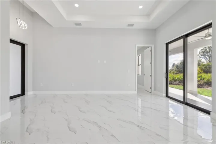 Spare room featuring a raised ceiling, plenty of natural light, and ceiling fan