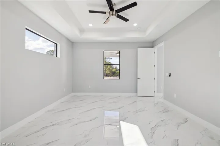 Unfurnished room featuring ceiling fan and a tray ceiling