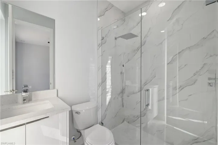Bathroom featuring vanity, toilet, and a shower with shower door