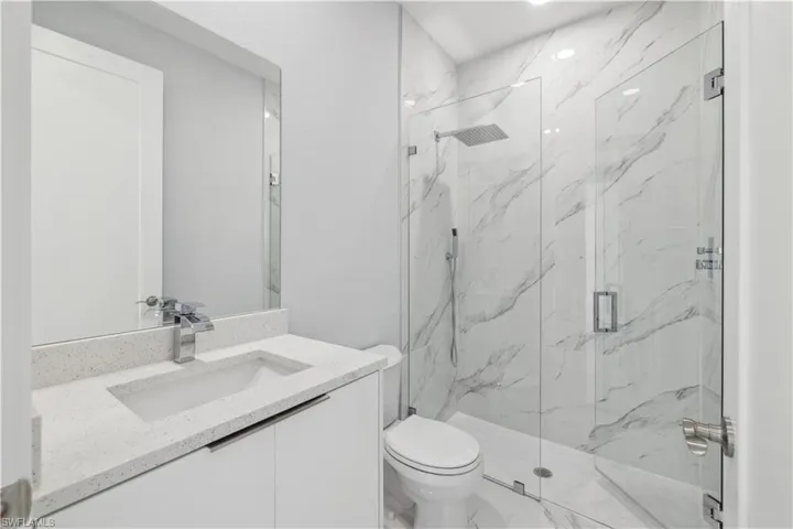 Bathroom featuring an enclosed shower, vanity, and toilet
