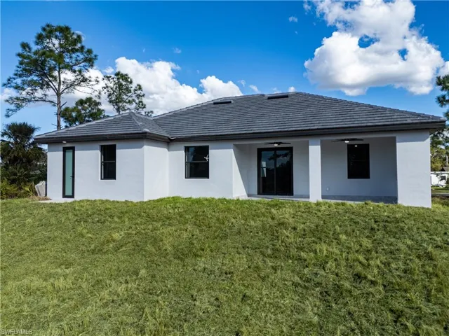 Rear view of property featuring a yard and ceiling fan