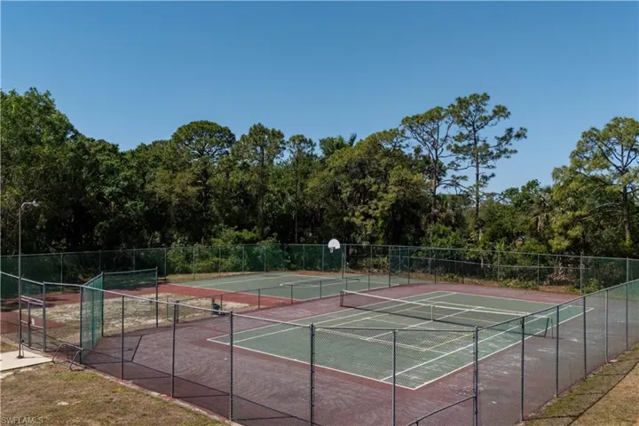 View of tennis court with community basketball court and fence