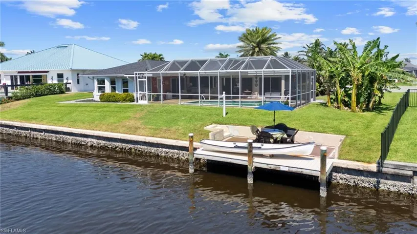 Dock area with glass enclosure, a patio, a yard, and a water view