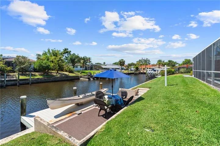View of dock featuring a lawn and a water view