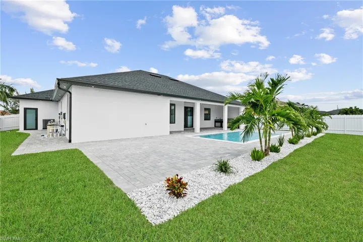 Back of house featuring a lawn, a fenced in pool, and a patio