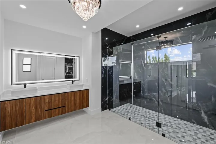 Bathroom featuring vanity, plenty of natural light, an enclosed shower, and an inviting chandelier