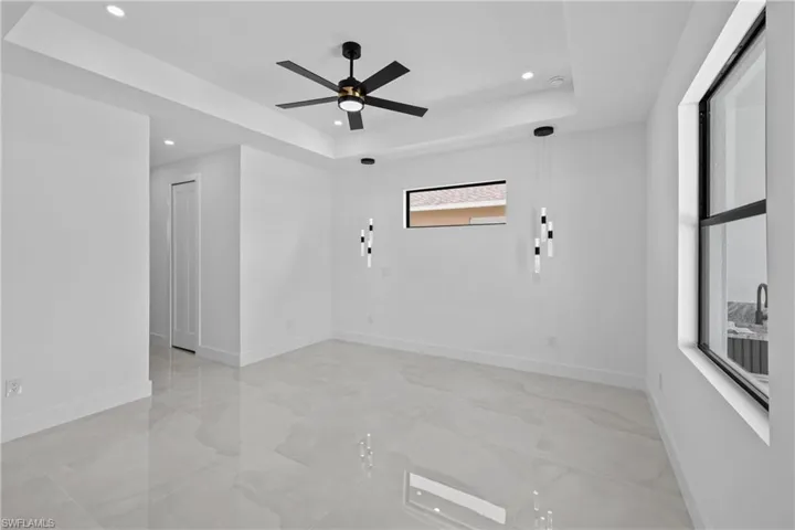 Empty room featuring ceiling fan and a tray ceiling