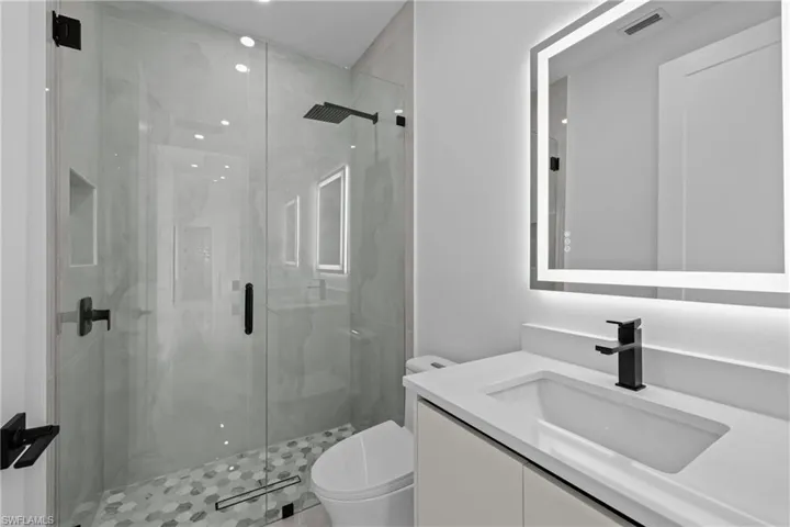 Bathroom featuring vanity, toilet, and a shower with shower door