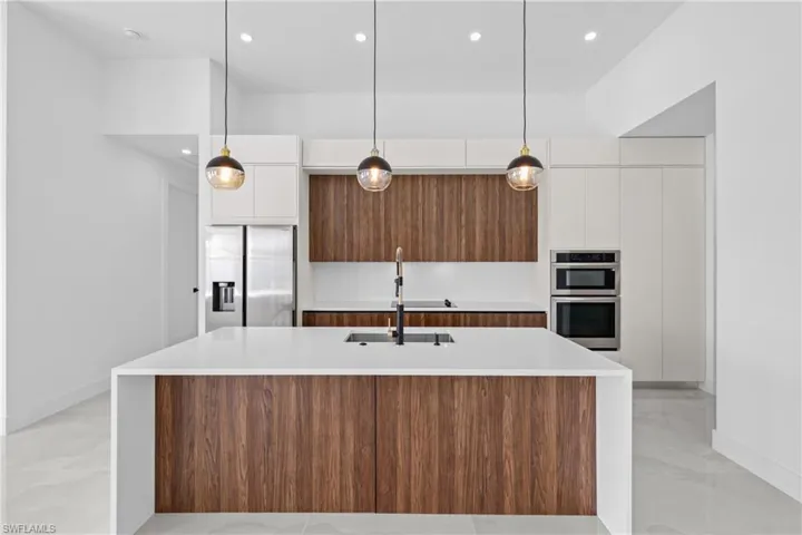 Kitchen featuring an island with sink, stainless steel appliances, sink, and white cabinetry