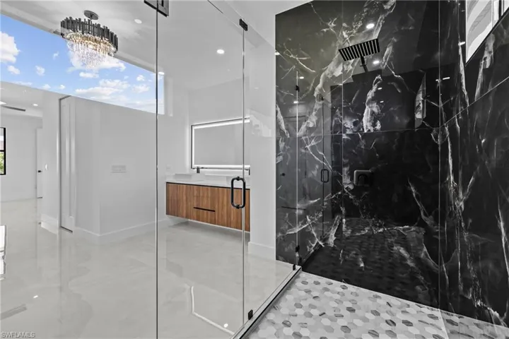 Bathroom featuring vanity, a notable chandelier, and a shower with shower door