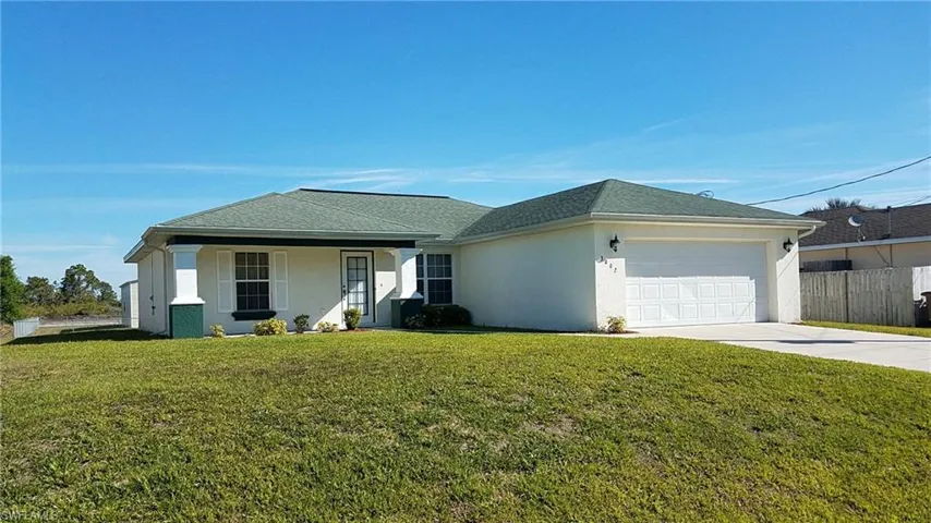 Front exterior with a green shingle roof, white stucco finish, and a two-car garage