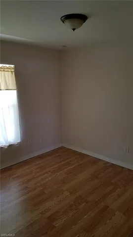 Wood-finish flooring with neutral wall tones and a flush-mount ceiling light