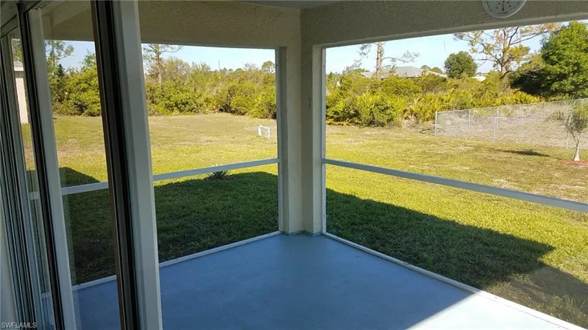 Screened porch with sliding glass door access, concrete flooring, and a spacious backyard