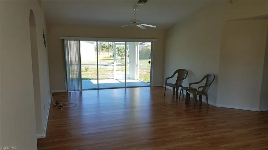 Vaulted ceilings, wood-finish flooring, sliding glass doors, ceiling fan, and a screened outdoor area