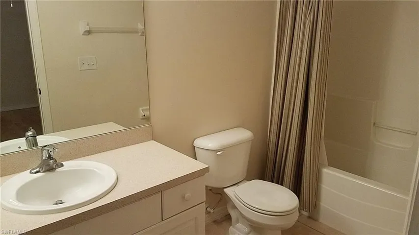 Bathroom featuring a vanity with an integrated sink, broad wall mirror, toilet, and a shower-tub combination