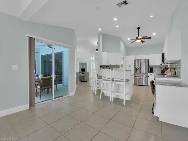 Open-concept kitchen featuring white cabinetry, stainless steel appliances, and a central island with bar seating