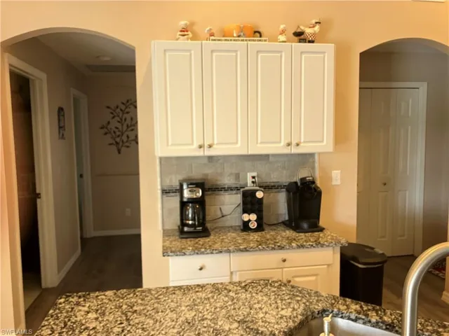 Kitchen featuring stone countertops, dark hardwood / wood-style floors, and white cabinetry