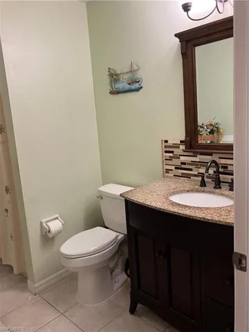 Bathroom featuring vanity, tasteful backsplash, toilet, and tile patterned floors