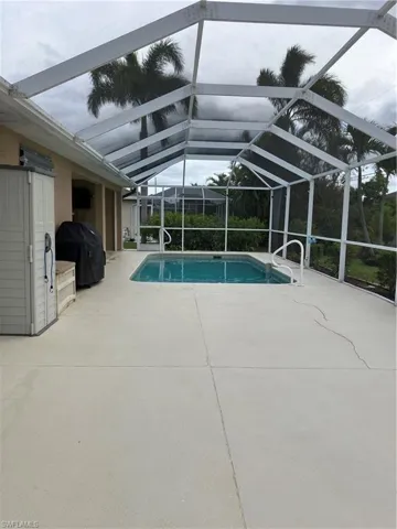 View of swimming pool featuring area for grilling, a patio area, and glass enclosure