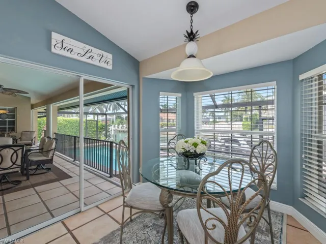 Dining area with lofted ceiling, light tile patterned flooring, plenty of natural light, a sunroom, and a water view