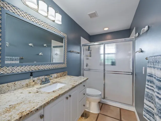 Bathroom with a shower stall, light tile patterned floors, and vanity