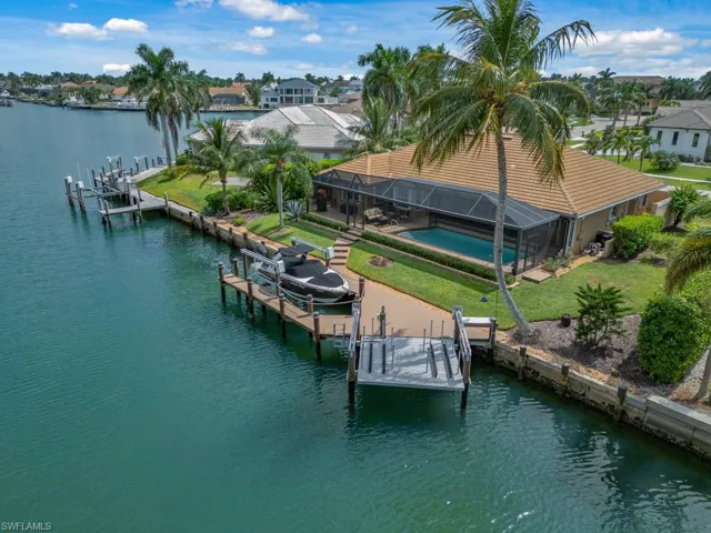 Dock area with boat lift, a water view, glass enclosure, and an outdoor pool